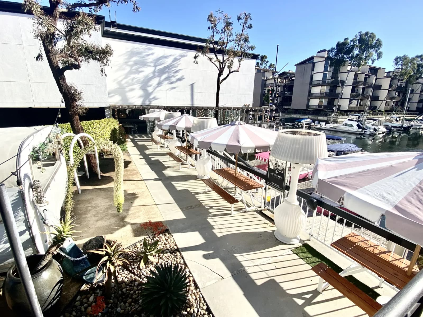 The dockside patio with pink umbrellas and benches at Marina Pacifica