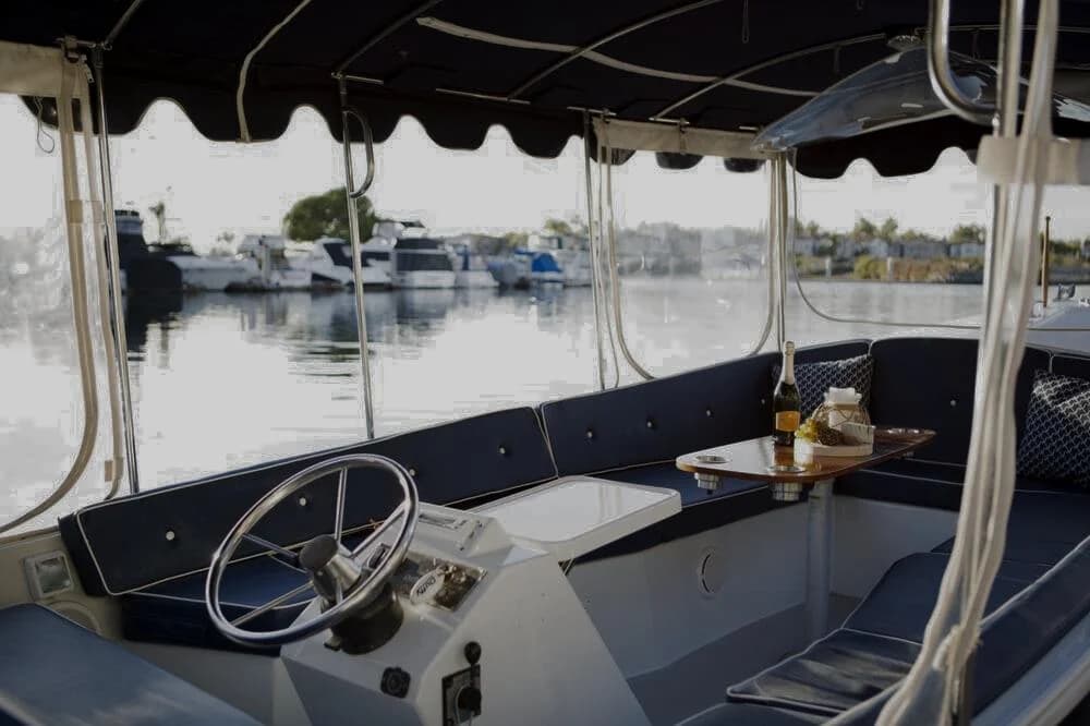 Inside a Duffy: the helm, blue cushions, champagne and charcuterie on the table