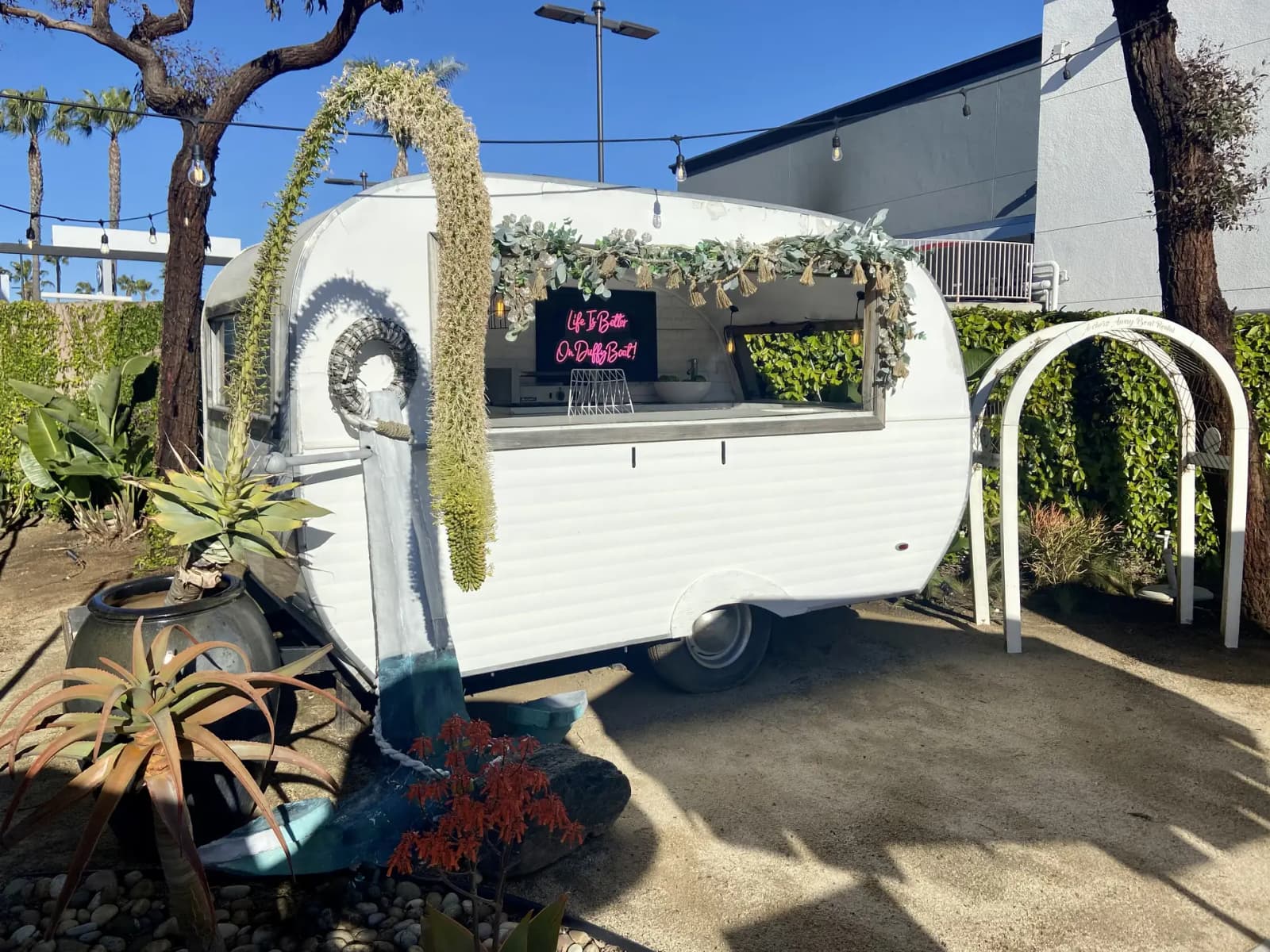 A vintage white trailer bar with a Let's Party neon sign