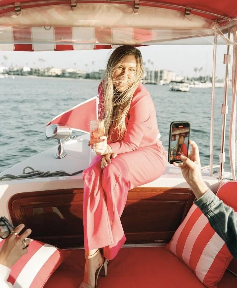 A guest in a pink suit aboard a pink-canopy Duffy at golden hour